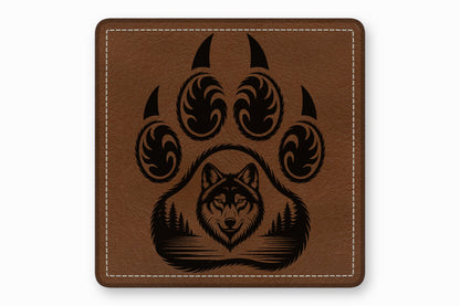Brown leather square patch with white edge stitching and a black engraved wolf paw and forest design.