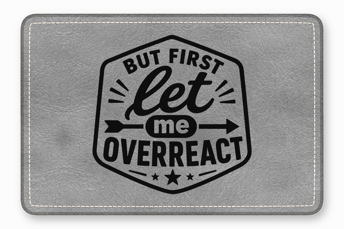 Gray faux leather patch with white stitched border and black printed text reading BUT FIRST let me OVERREACT.