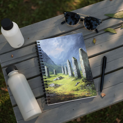Spiral-bound notebook with a landscape painting of standing stones in a grassy valley.