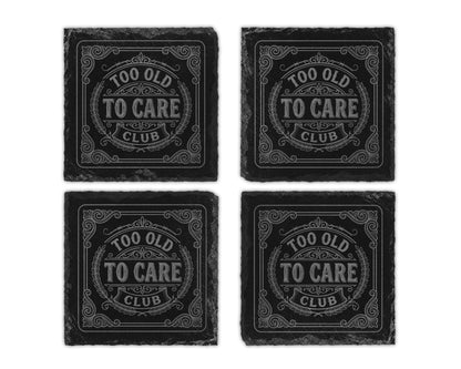 Four slate coasters engraved with "TOO OLD TO CARE CLUB" in a decorative design.