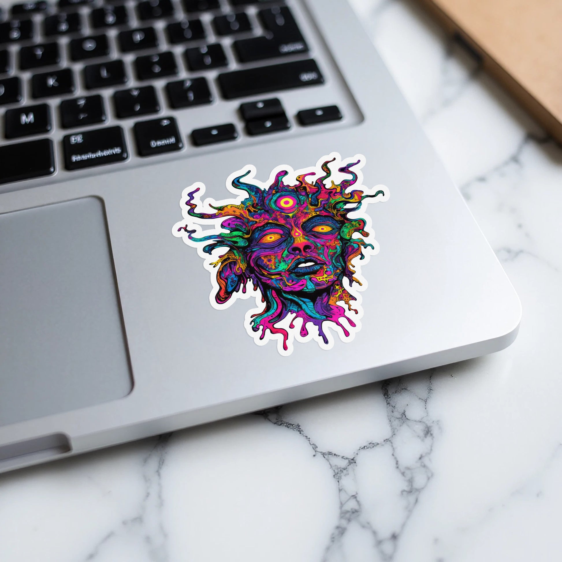 Colorful psychedelic face sticker with vibrant, swirling hair on a laptop.