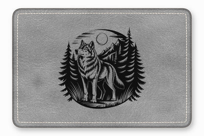 A gray leather pad featuring an embossed black design of a wolf in a forest.
