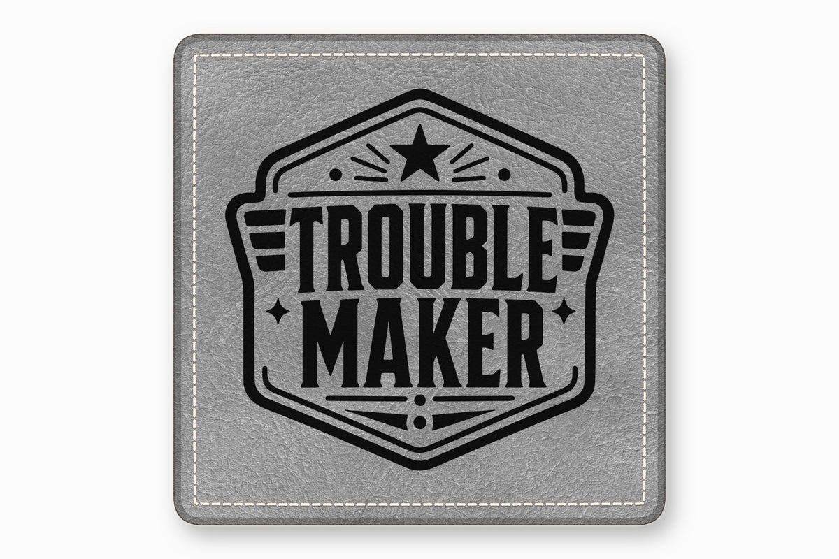 Square grey leather patch with white stitched border featuring a black Trouble Maker emblem.