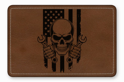 Brown leather rectangular patch with white stitched border, featuring a black engraved mechanic skull holding two wrenches over a distressed American flag.