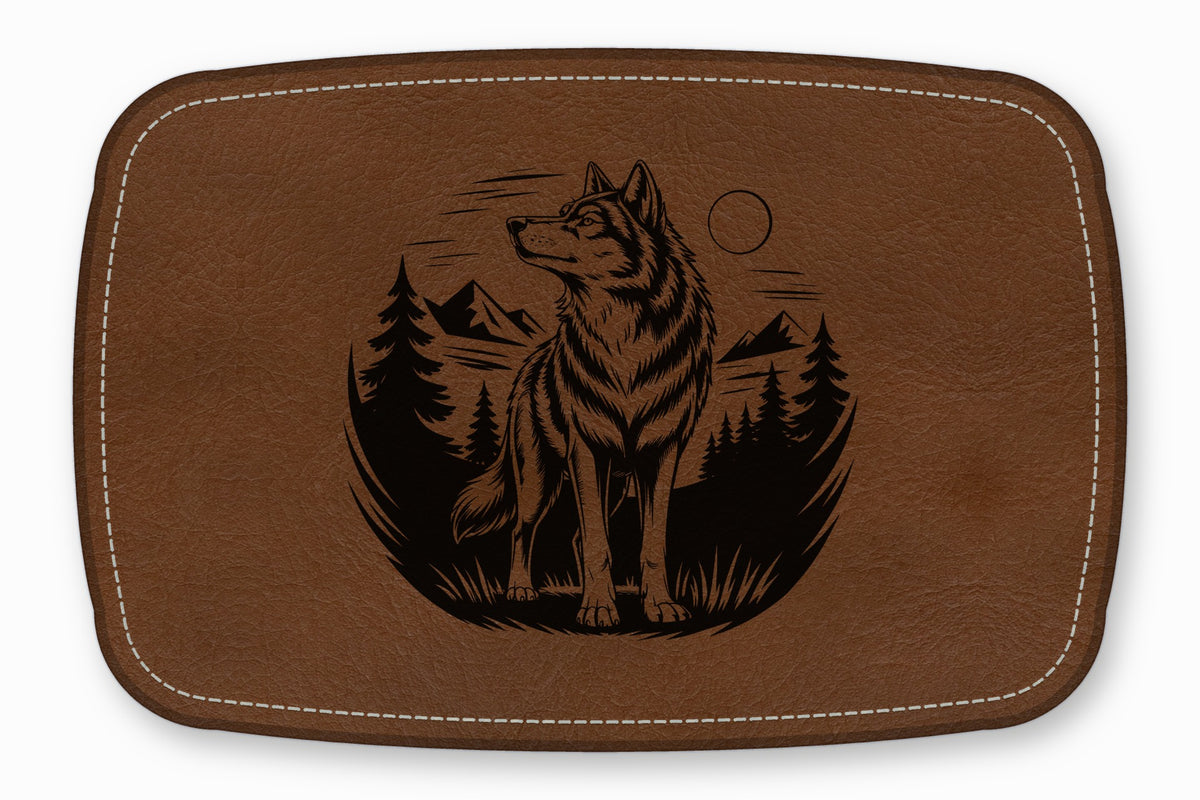 Brown leather patch with rounded corners featuring a black engraved illustration of a wolf, mountains, and trees.
