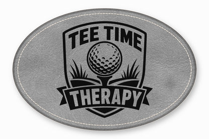 Gray oval leather patch featuring a black golf graphic and the text Tee Time Therapy.
