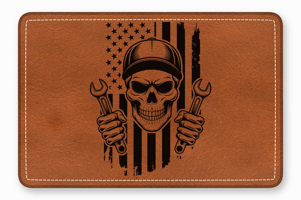 Brown leather patch featuring a black engraved mechanic skull wearing a cap and holding wrenches against an American flag.