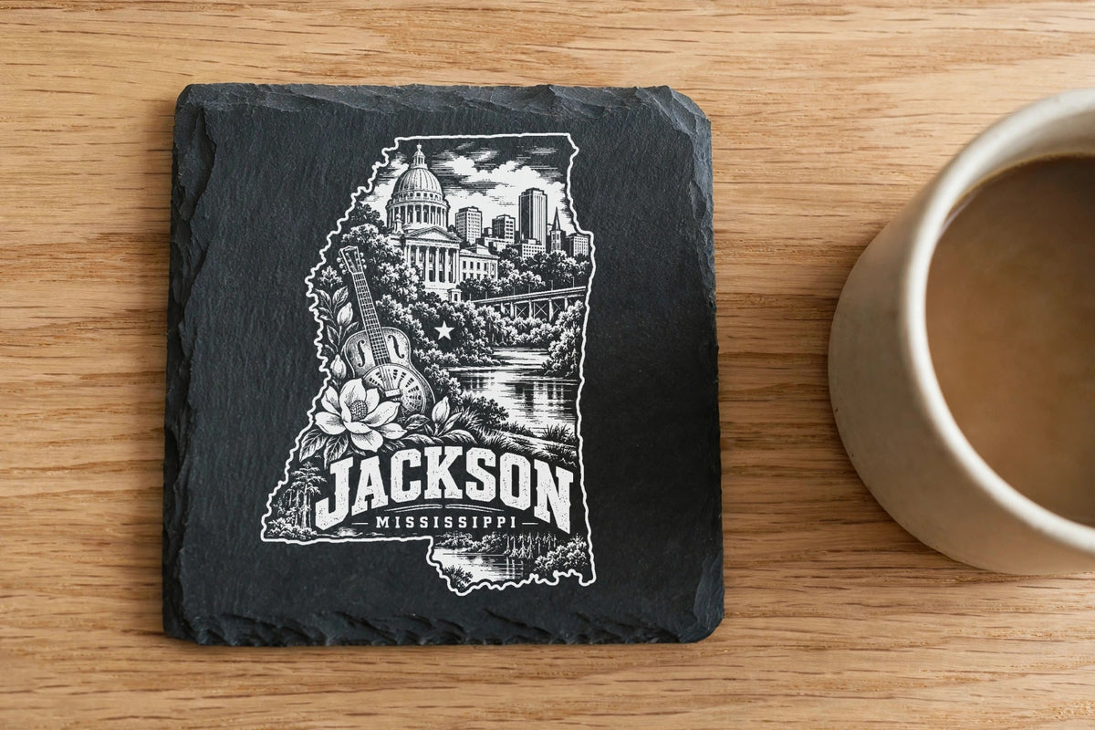 A square slate coaster engraved with an outline of Mississippi, Jackson city landmarks, and text.