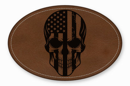 Oval brown leather patch with white stitched border featuring a black skull graphic overlaid with the American flag.