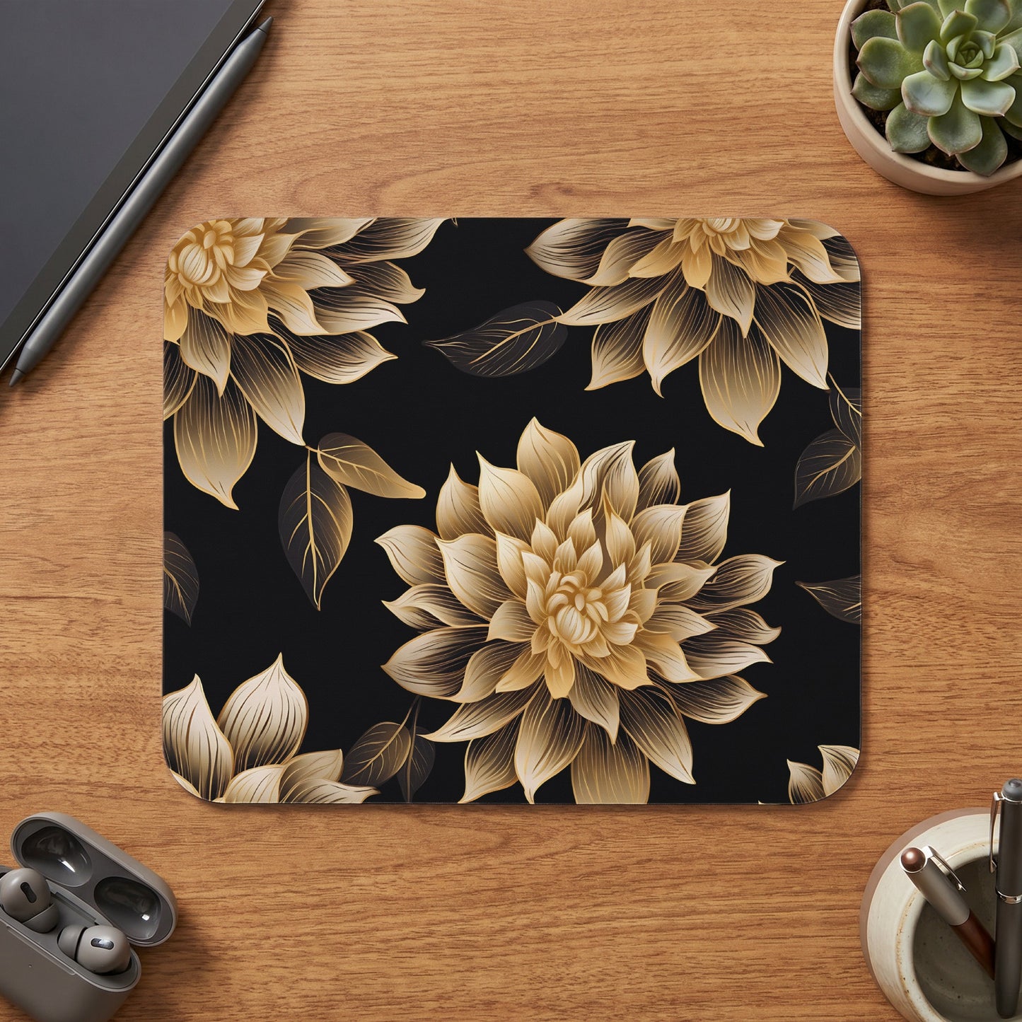 Black mousepad with gold floral pattern, on a wooden desk.