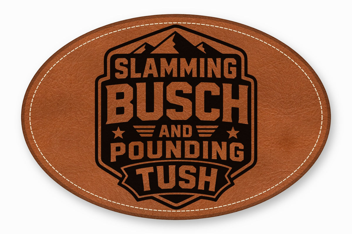 Oval brown leather patch with white stitched border and black engraved text reading Slamming Busch and Pounding Tush.
