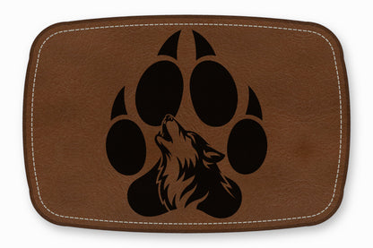 Brown leather patch with white stitched border, featuring a black silhouette of a howling wolf inside a paw print.