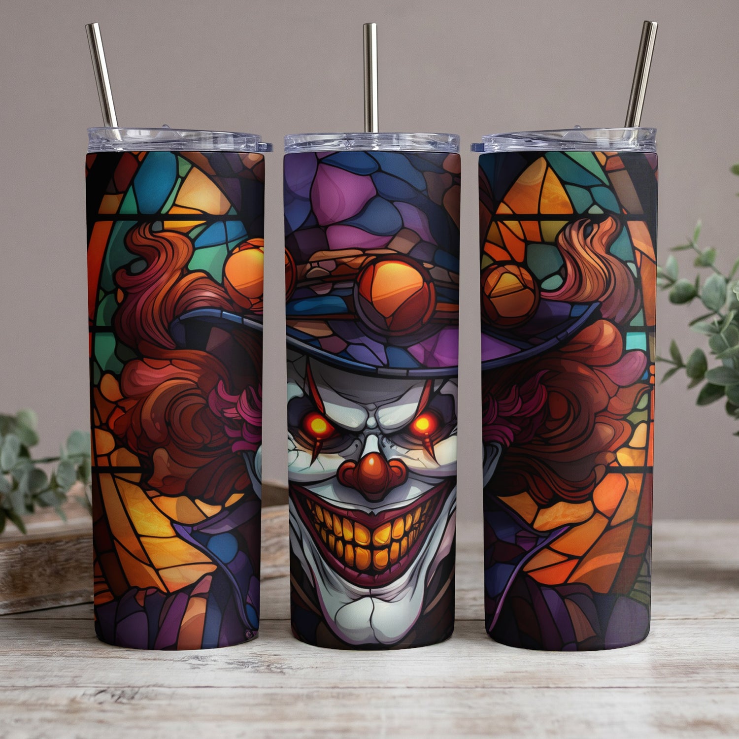 Three tumblers with a creepy clown stained glass design and metal straws.