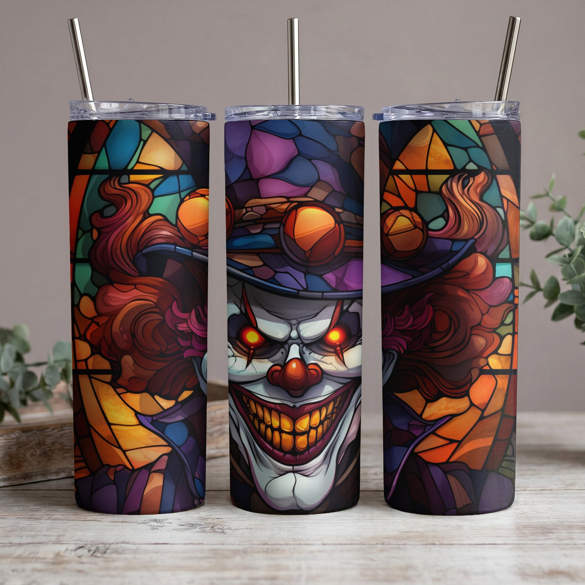 Three tumblers with a creepy clown stained glass design and metal straws.