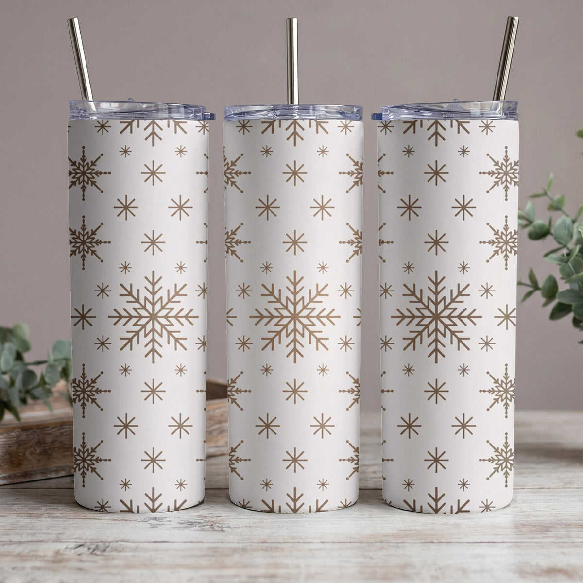 Three tumblers with a white background and a repeating brown snowflake pattern.