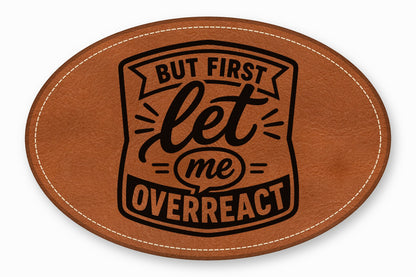 An oval brown leather patch with white stitched edges and black text reading But first let me overreact.