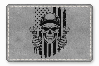 Grey rectangular leather patch featuring a black graphic of a mechanic skull holding wrenches before an American flag.