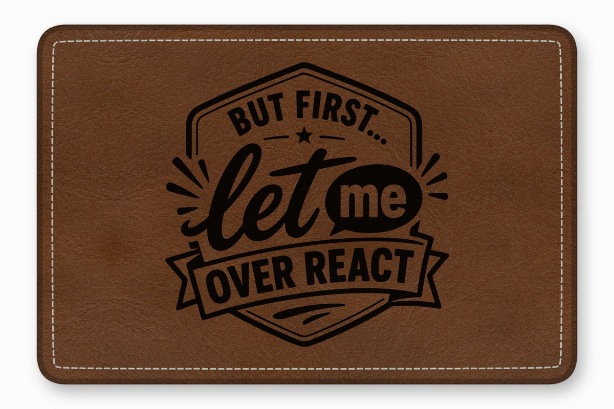 A brown faux leather patch with white stitched borders features black text reading "BUT FIRST... let me OVER REACT".