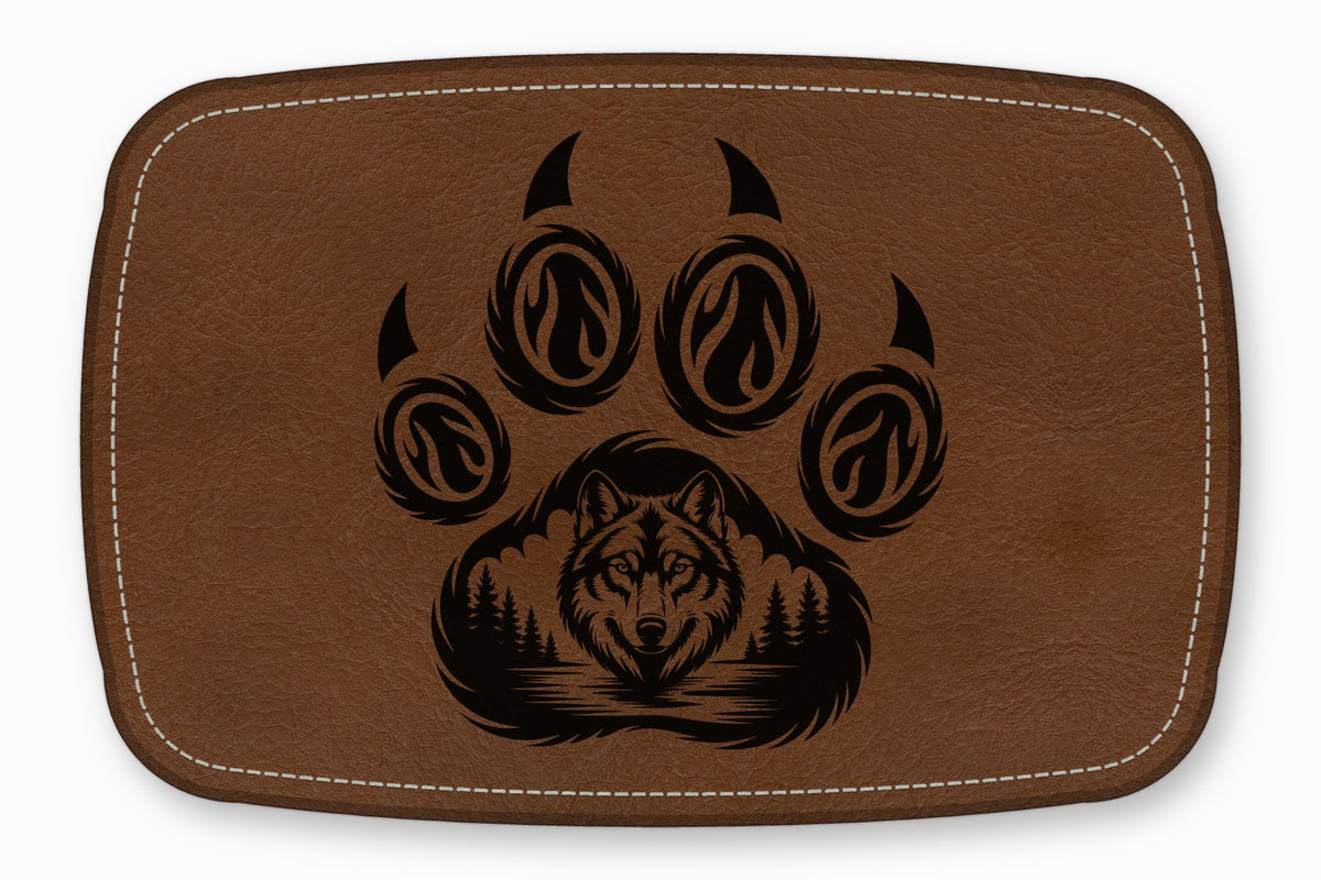 Brown leather patch featuring a black etched paw print enclosing a forest and wolf head.