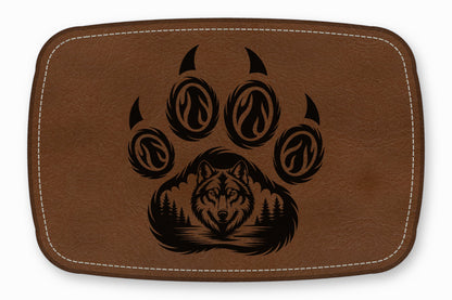 Brown leather patch featuring a black etched paw print enclosing a forest and wolf head.