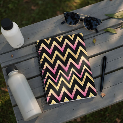 Notebook with black, pink, and gold chevron pattern on a wooden table.