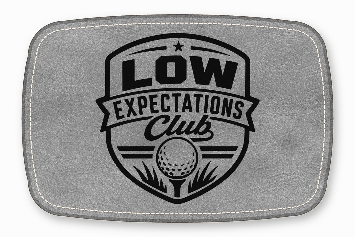 A gray leatherette patch featuring a black golf emblem with the text Low Expectations Club.