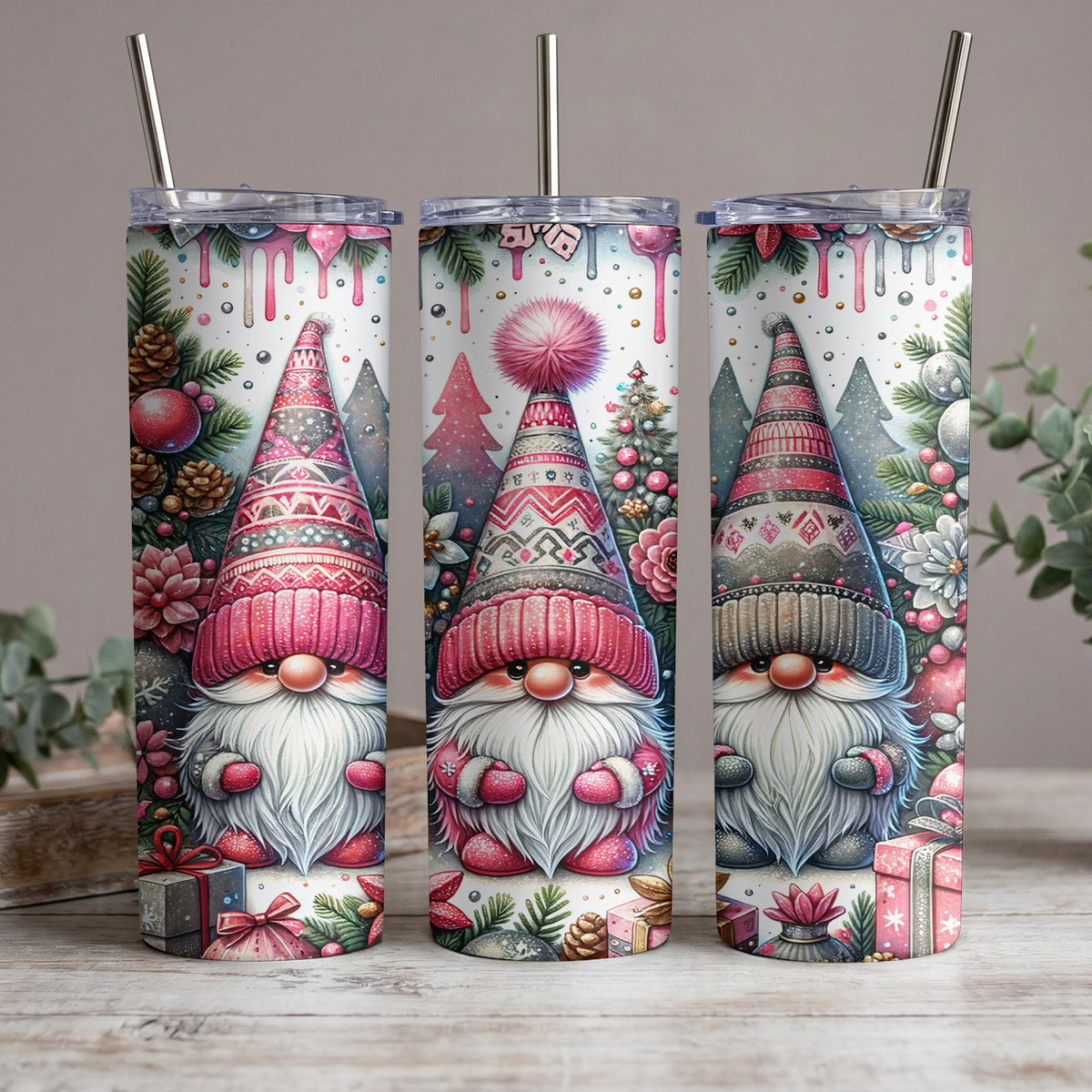 Three tumblers with festive gnome designs and metallic straws, decorated with winter foliage and gifts.