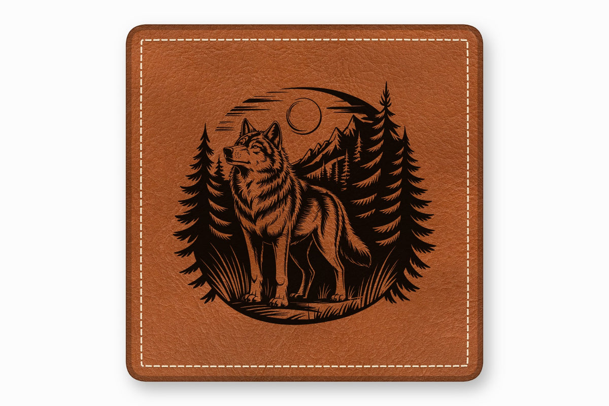 Brown square leather coaster with a black engraved design of a wolf standing in a forest with mountains and moon.