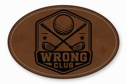 Oval brown leather patch with white stitching and a black golf-themed crest featuring crossed clubs and the text "Wrong Club".