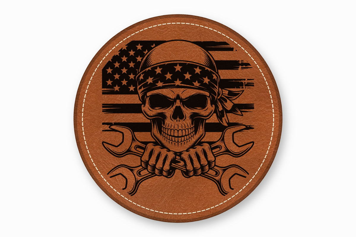 A round brown leather patch features a black laser-engraved skull wearing a bandana and crossed wrenches over an American flag.