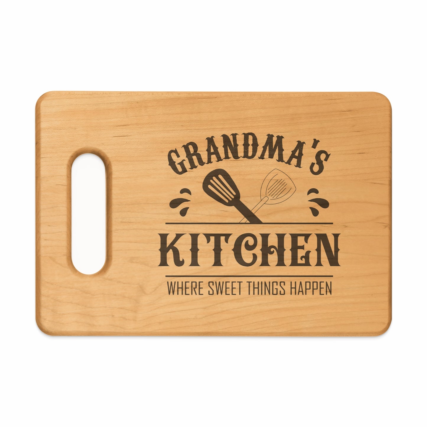 Wooden cutting board with "Grandma's Kitchen Where Sweet Things Happen" text and spatulas.