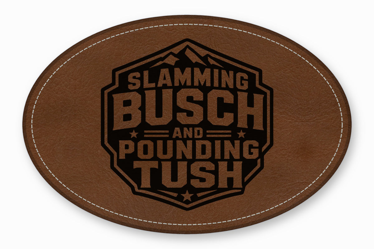 Oval brown leather patch with white stitched border featuring black engraved text reading Slamming Busch and Pounding Tush inside a mountain hexagon emblem.