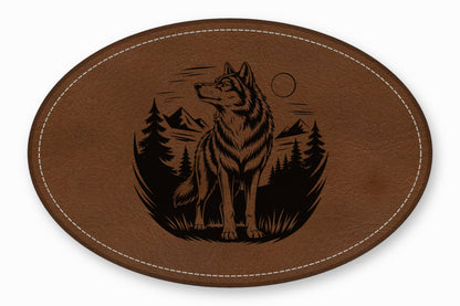 An oval brown leather patch featuring a laser-engraved design of a wolf in a forest.
