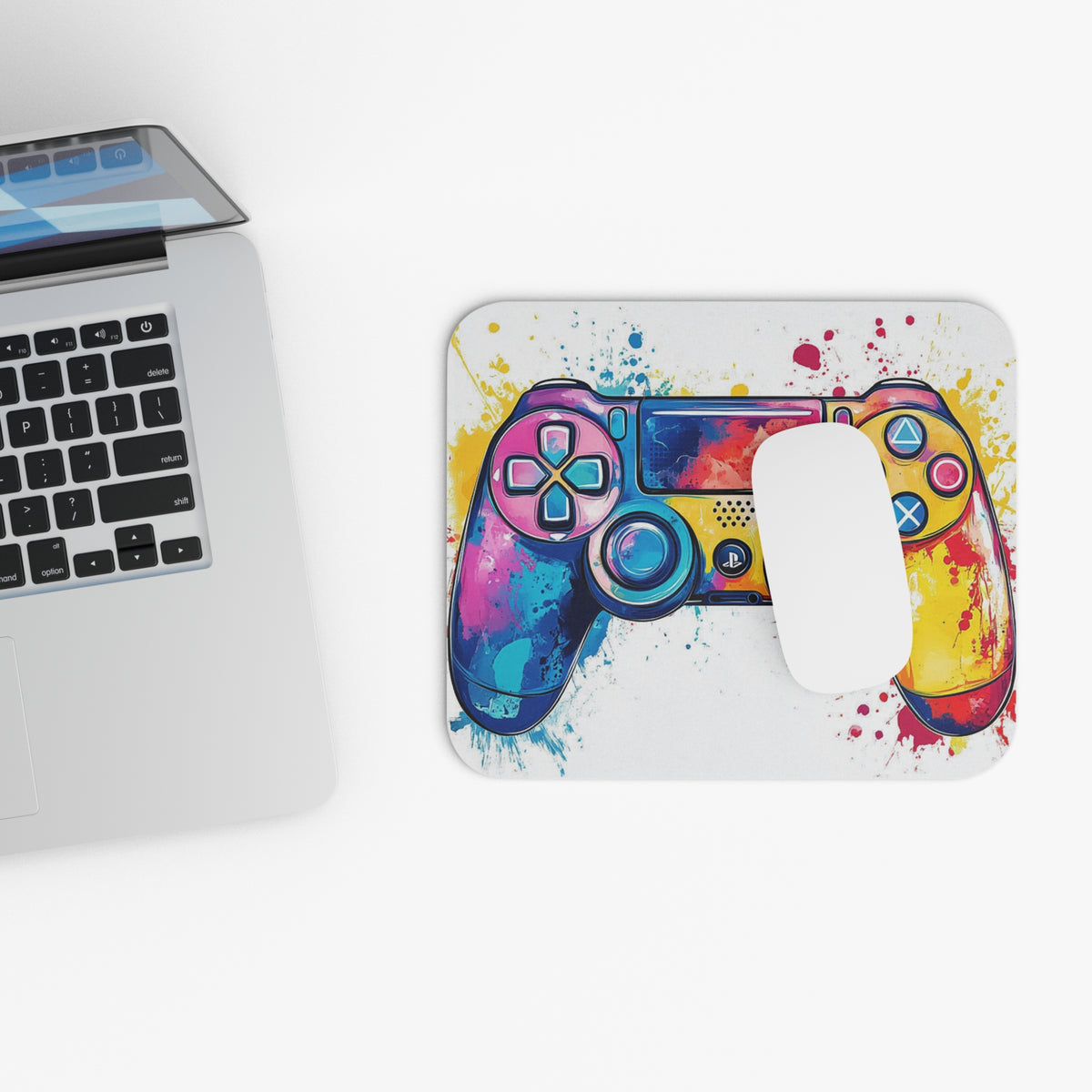 Watercolor game controller design on a mousepad next to a laptop.