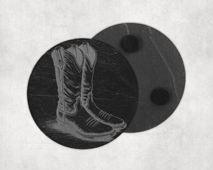 Engraved cowboy boots design on a round slate coaster with two black felt feet.