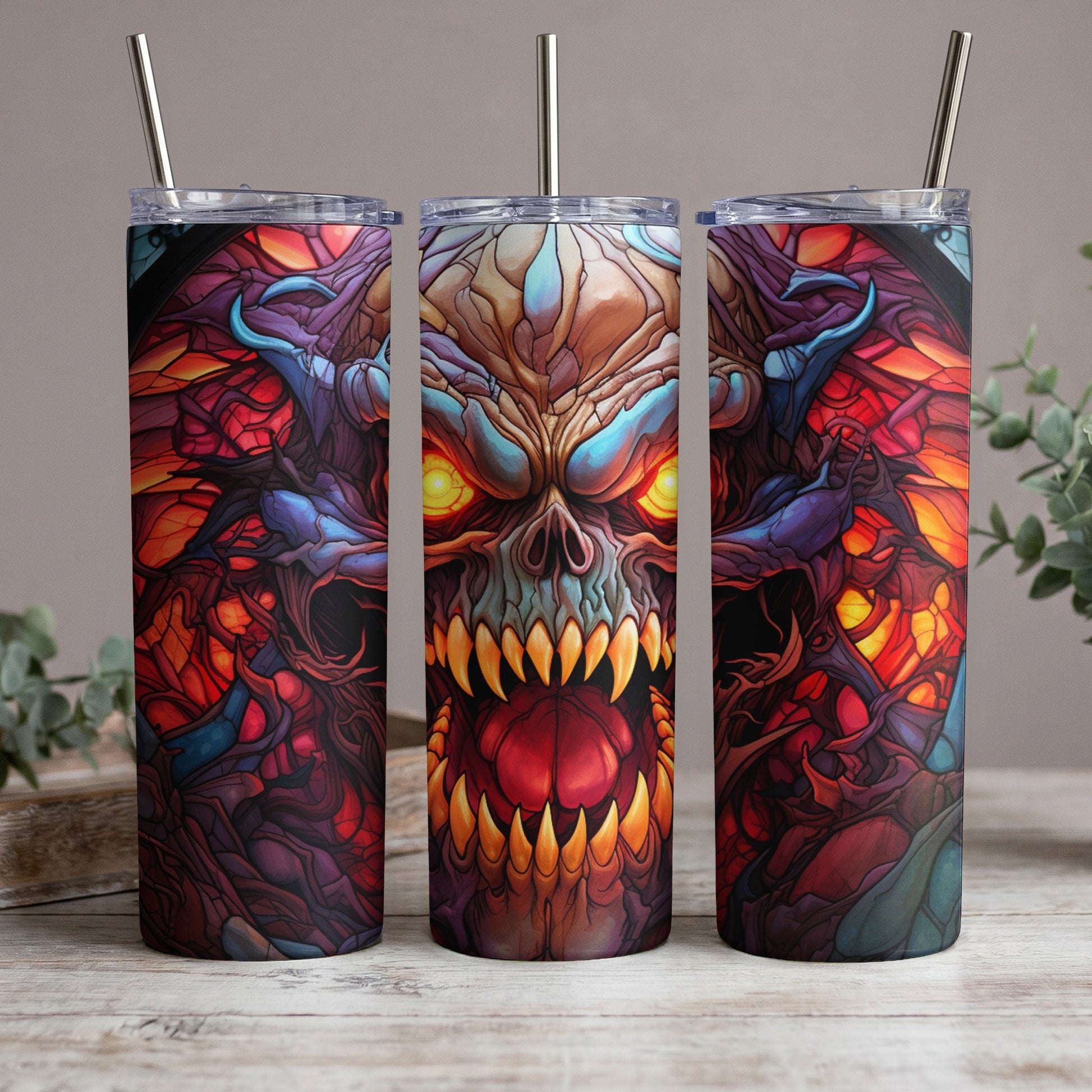 Three tumblers with a demonic skull design in vibrant red, blue, and yellow hues.