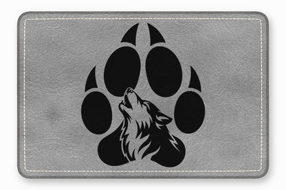 A grey textured leather patch features a black graphic of a howling wolf within a paw print.