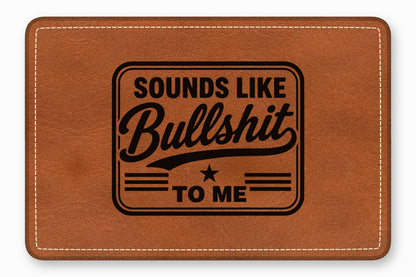 Brown leather patch with white stitching and the engraved text Sounds Like Bullshit To Me.