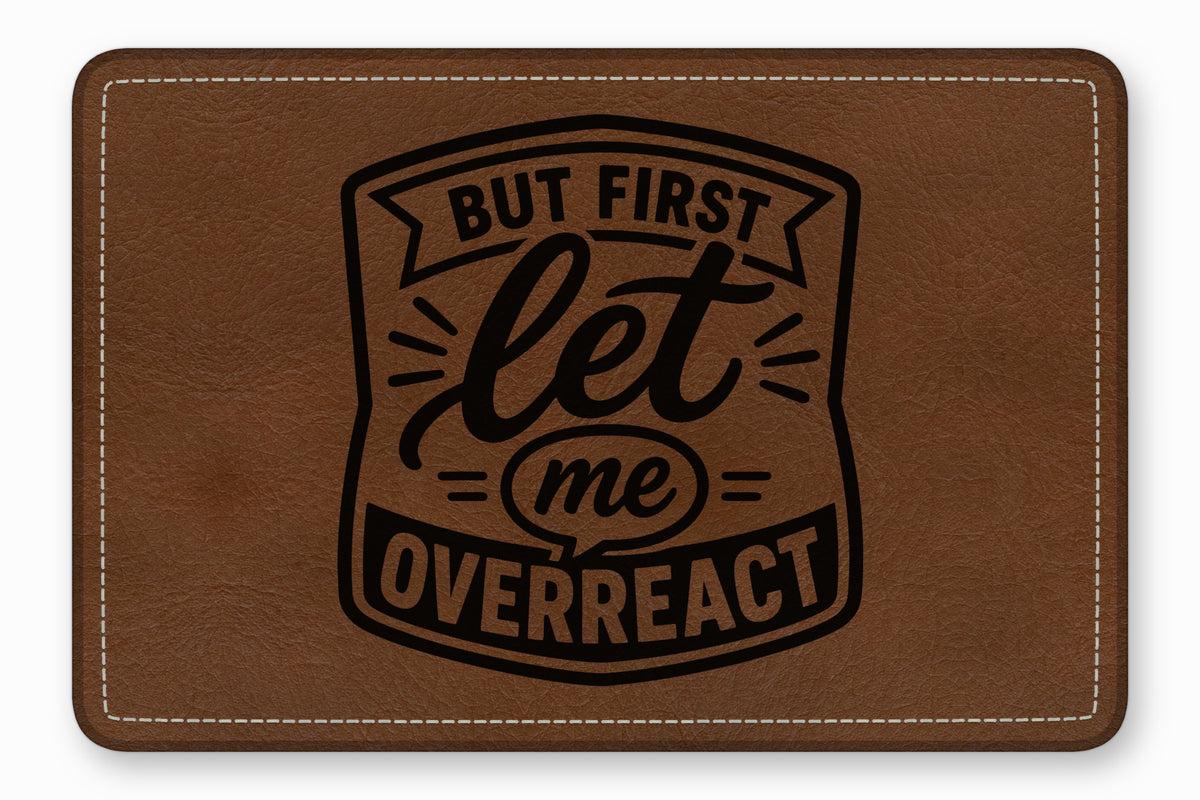 Brown faux leather patch with white stitched border and black engraved text reading But first let me overreact.