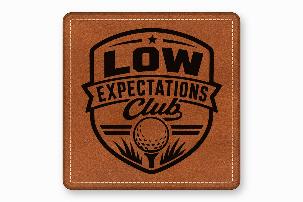 Brown square leather patch featuring a black crest with the text Low Expectations Club and a golf ball.