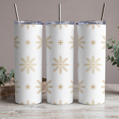 Three white tumblers with gold snowflake pattern and metal straws.