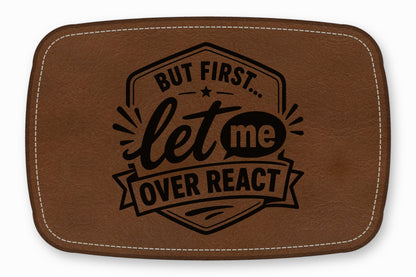 Brown leather patch with white stitching and the engraved text But First Let Me Overreact.