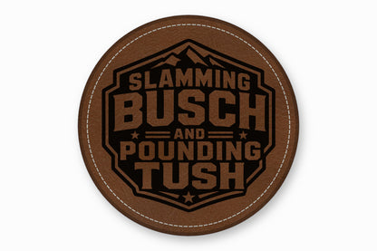 Round brown leatherette patch with white stitching and the engraved text Slamming Busch and Pounding Tush.