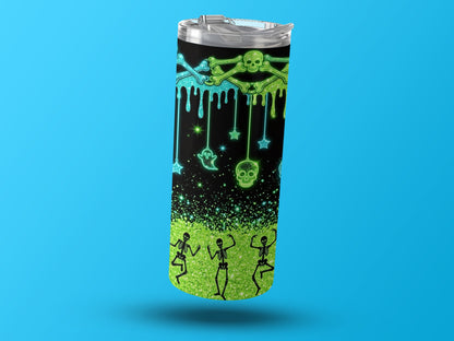 Tumbler with dripping skulls, bones, ghosts, stars, and dancing skeletons on black and green glitter background.