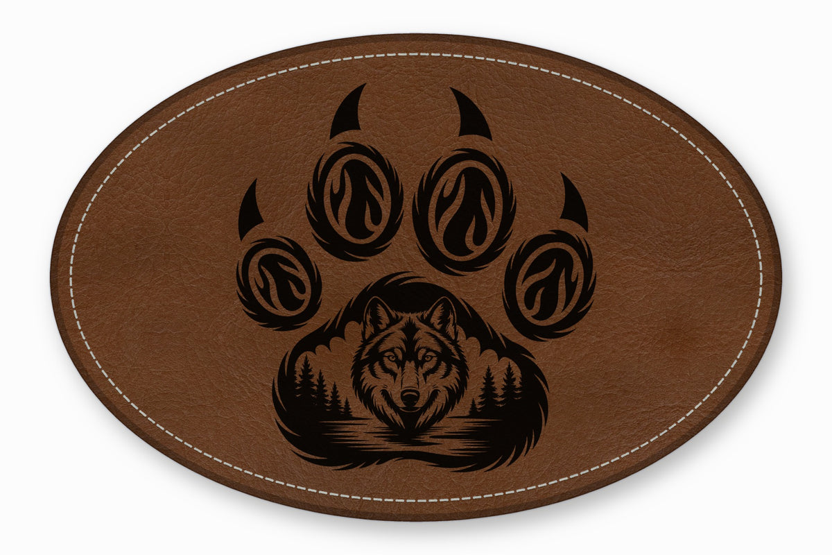 Brown oval leather patch featuring a black laser-engraved wolf face and pine tree paw print design.
