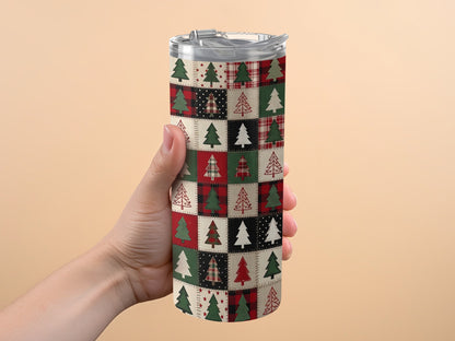 Hand holding a tumbler with a Christmas tree patchwork quilt pattern.