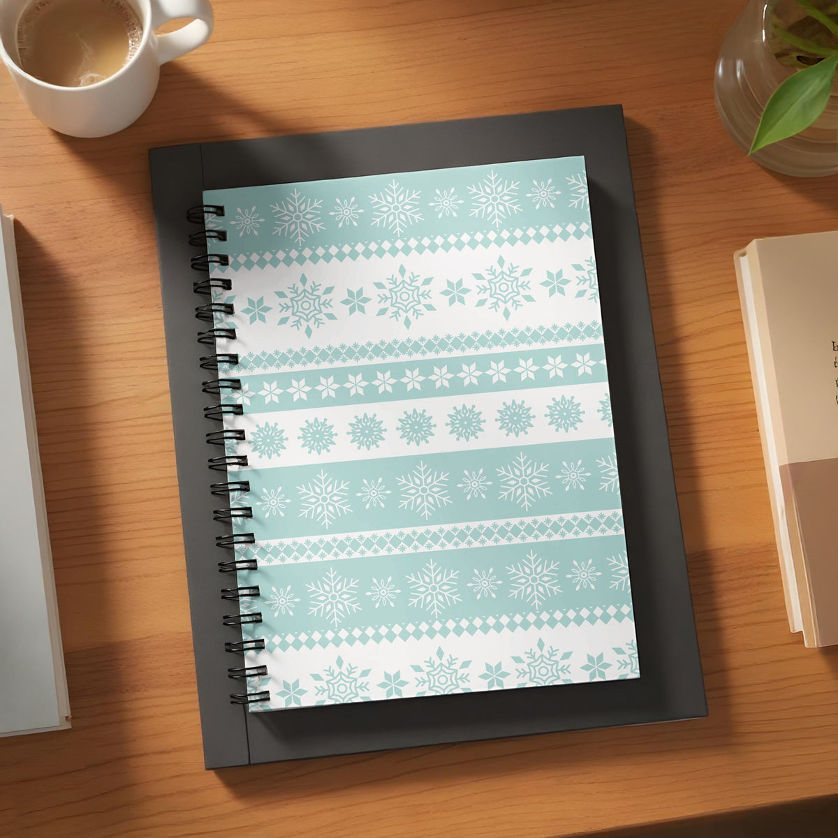 Notebook with light blue and white snowflake pattern on a wooden desk.