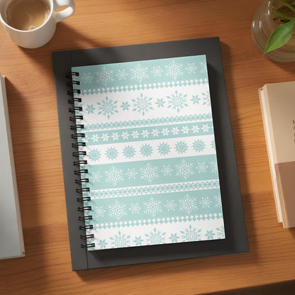 Notebook with light blue and white snowflake pattern on a wooden desk.