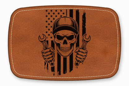 Brown leather patch featuring a black engraved mechanic skull holding two wrenches against an American flag.