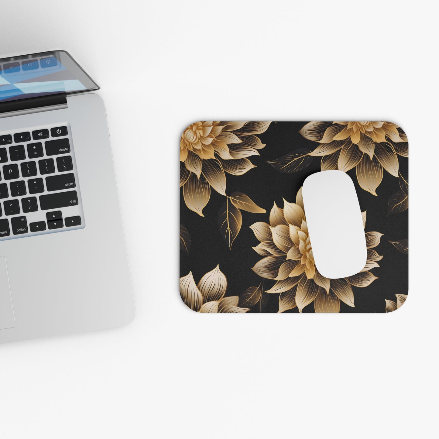Mousepad with gold floral pattern next to a laptop and white mouse.